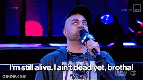 A Man Speaking Into A Microphone That Says I 'M Still Alive GIF