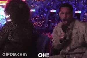 A Man Speaking Into A Microphone While A Woman Stands Behind Him With The Word Oh Written On The Bottom GIF