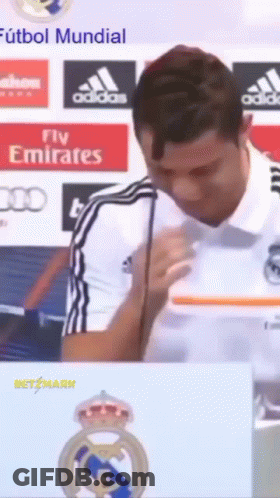 A Man Speaking Into A Microphone With A Fly Emirates Logo In The Background GIF