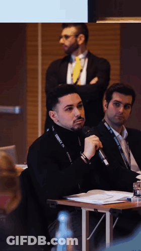 A Man Speaking Into A Microphone With A Lanyard Around His Neck That Says Connect GIF
