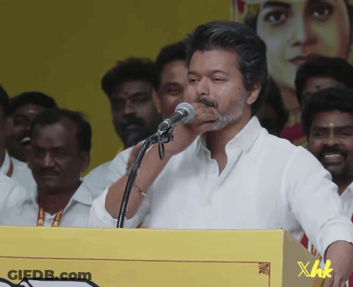 A Man Speaking Into A Microphone With Xhk Written On A Yellow Box GIF