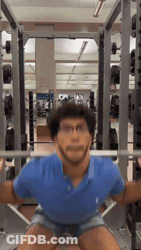 A Man Squatting With A Barbell In A Gym With A Star On The Wall GIF
