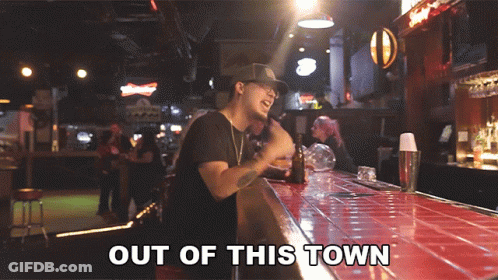 A Man Standing At A Bar With Out Of This Town Written On The Bottom GIF
