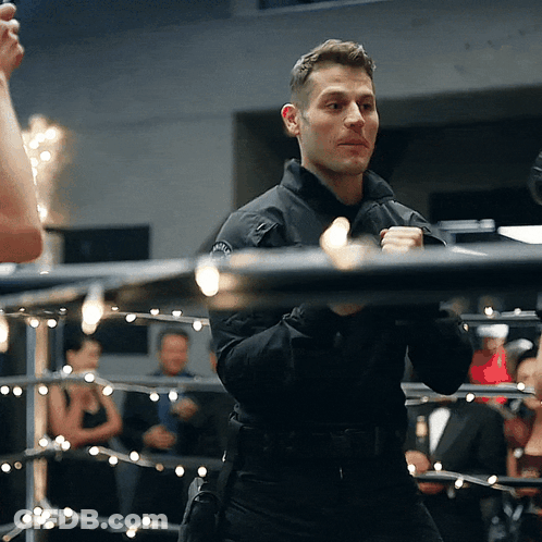 A Man Standing In A Boxing Ring With A Badge On His Chest GIF