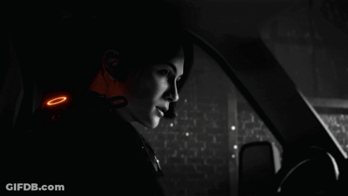A Man Standing In A Dark Room With A Blue Light Shining On Him GIF