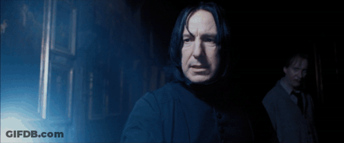 A Man Standing In A Dark Room With A Light Shining On Him GIF