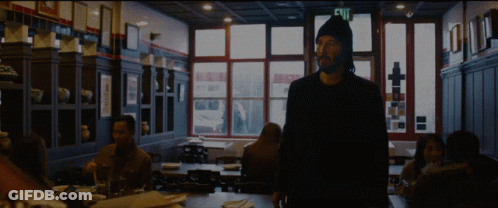 A Man Standing In A Dark Room With A Sign That Says Exit GIF
