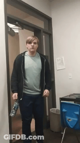A Man Standing In A Doorway Holding A Water Bottle That Says ' I 'M Sorry ' On It GIF