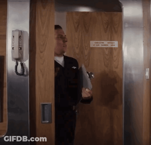 A Man Standing In A Doorway With A Sign That Says Executive Officer GIF