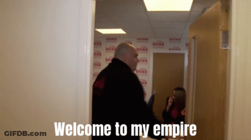 A Man Standing In A Hallway With The Words Welcome To My Empire Written On The Wall Behind Him GIF