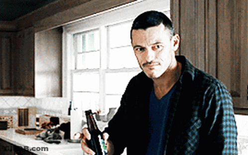 A Man Standing In A Kitchen Holding A Bottle GIF