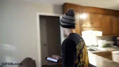 A Man Standing In A Kitchen Wearing A Black Shirt That Says Release GIF