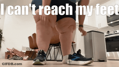 A Man Standing In A Kitchen With The Words " I Can 'T Reach My Feet " GIF