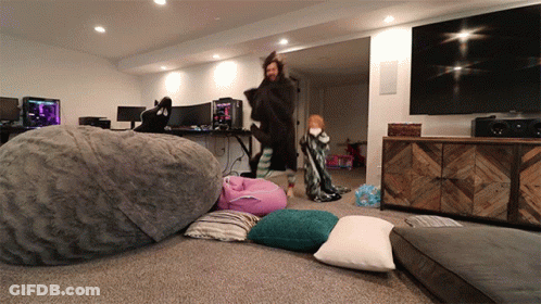 A Man Standing In A Living Room With A Large Bean Bag Chair GIF