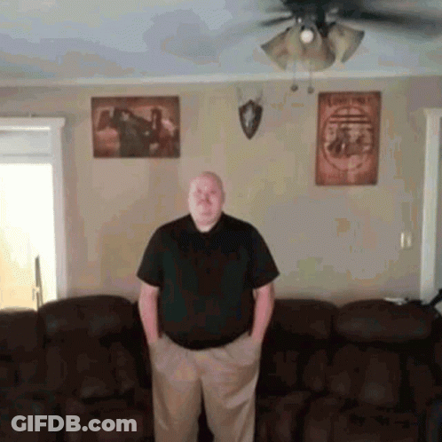 A Man Standing In A Living Room With His Hands In His Pockets . GIF