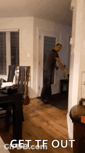 A Man Standing In A Living Room With The Words Get Tf Out GIF