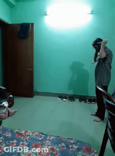 A Man Standing In A Room With A Floral Blanket On The Floor GIF