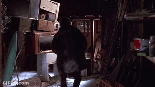 A Man Standing In A Room With A Stack Of Appliances GIF