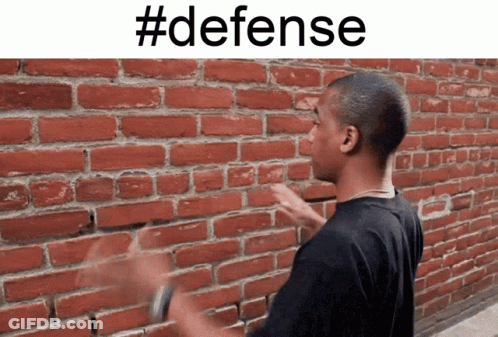 A Man Standing In Front Of A Brick Wall With #Defense Written Above Him GIF