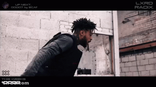 A Man Standing In Front Of A Brick Wall With The Words Lxrd Radix On The Top GIF