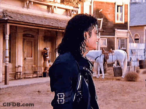 A Man Standing In Front Of A Building With A White Horse GIF
