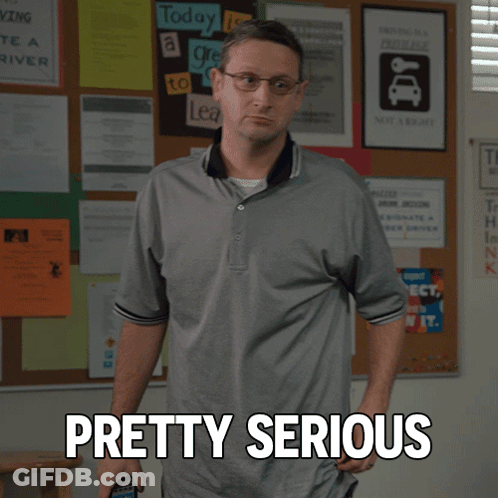 A Man Standing In Front Of A Bulletin Board With Pretty Serious Written On It GIF