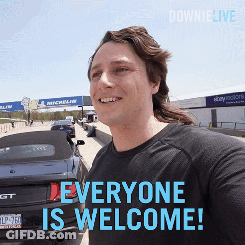 A Man Standing In Front Of A Car With The Words Everyone Is Welcome GIF