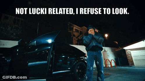 A Man Standing In Front Of A Car With The Words " Not Lucki Related I Refuse To Look " Above Him GIF