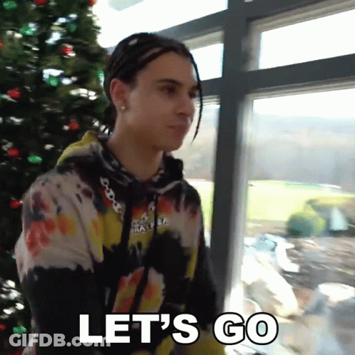 A Man Standing In Front Of A Christmas Tree With The Words Let 'S Go Below Him GIF