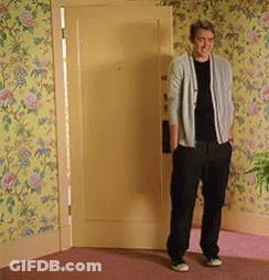 A Man Standing In Front Of A Door With Floral Wallpaper On The Wall GIF
