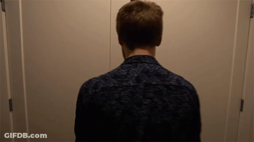 A Man Standing In Front Of A Door With His Back To The Camera GIF