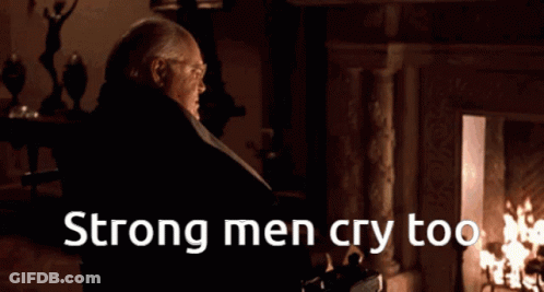 A Man Standing In Front Of A Fireplace With The Words Strong Men Cry Too On The Bottom GIF