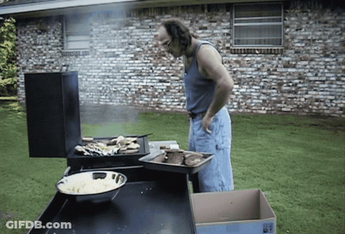 A Man Standing In Front Of A Grill With A Box In Front Of Him That Says " Fragile " GIF