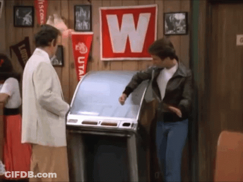 A Man Standing In Front Of A Jukebox With A W On It GIF