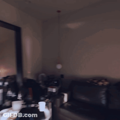 A Man Standing In Front Of A Large Mirror In A Dark Room GIF