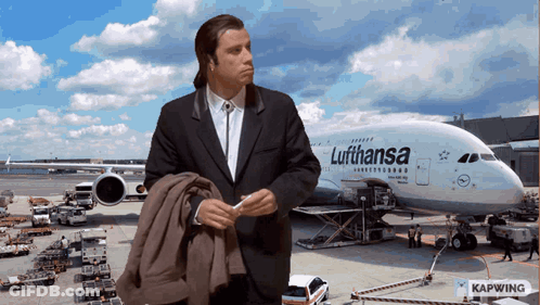 A Man Standing In Front Of A Lufthansa Plane GIF