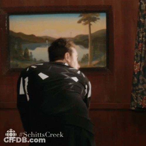 A Man Standing In Front Of A Painting That Says Schitts Creek On The Bottom GIF