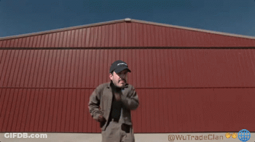 A Man Standing In Front Of A Red Building That Says Wutrade Clan On It GIF