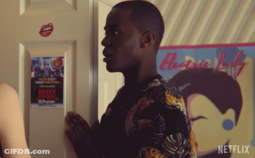 A Man Standing In Front Of A Rocky Horror Show Poster On A Door GIF