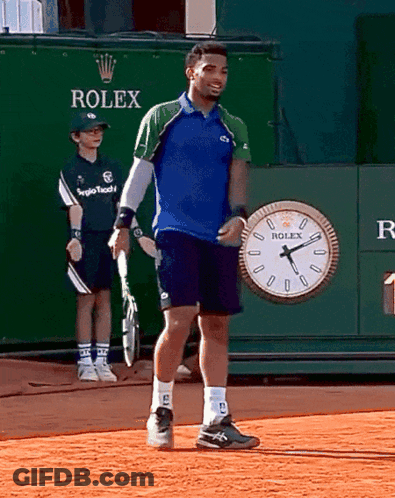 A Man Standing In Front Of A Rolex Clock GIF