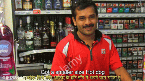 A Man Standing In Front Of A Shelf Of Liquor And Cigarettes With A Caption That Says Got A Smaller Size Hot Dog GIF