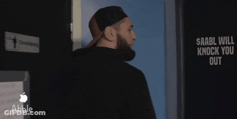 A Man Standing In Front Of A Sign That Says $ Aabll Will Knock You Out GIF