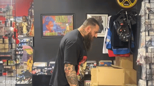A Man Standing In Front Of A Sign That Says Guns N Roses On It GIF