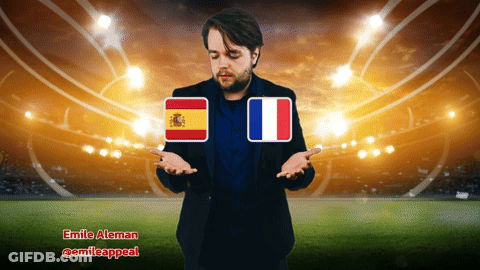 A Man Standing In Front Of A Stadium With A Spanish And French Flag GIF