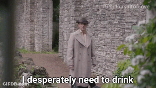 A Man Standing In Front Of A Stone Wall Says I Desperately Need To Drink GIF