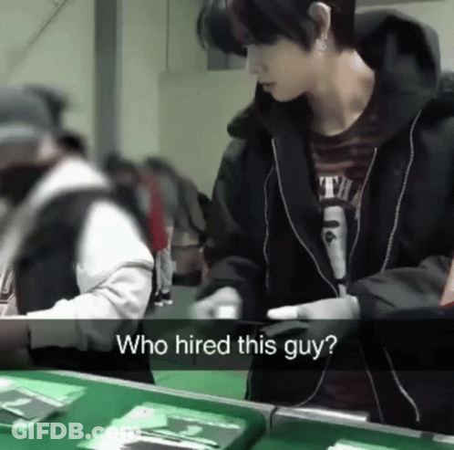 A Man Standing In Front Of A Table With The Words Who Hired This Guy On The Bottom GIF