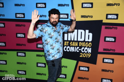 A Man Standing In Front Of A Wall That Says Imdb At San Diego Comic-Con 2019 GIF