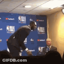 Man In Front Of NBA Finals Wall GIF