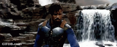 A Man Standing In Front Of A Waterfall Wearing A Blue Vest GIF