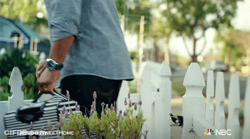 A Man Standing In Front Of A White Picket Fence With The Hashtag #Homesweethome On The Bottom GIF